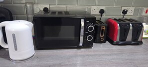 Una cocina equipada con microondas, tostadora y hervidor.