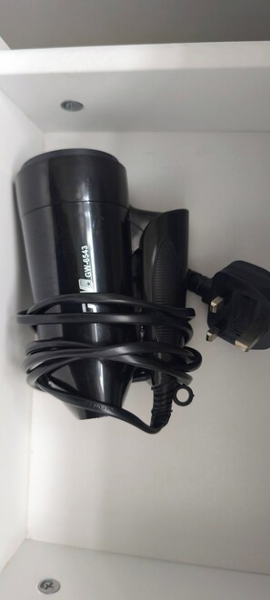 Eine schwarze, an der Decke befestigte Vorrichtung mit einer aufgewickelten Kabeltrommel, einem Netzteil und einem an der Wand montierten Schalter.