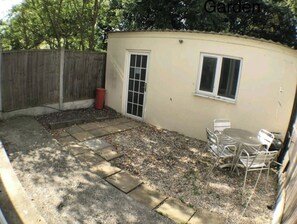 Una construcción pequeña de un solo piso con un patio, una puerta y una ventana.