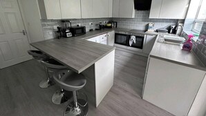 A modern kitchen with white cabinets, a grey countertop, and a built-in oven. - Room-cozy Small Room in City Centre and (Chelmsford)