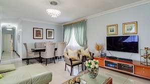 A modern living room with a dining area, a TV, and a chandelier. - The Quiet Hidden Gem (Johannesburg)