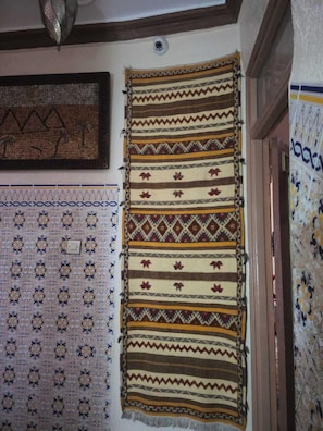 A wall with multiple patterned textiles, a ceiling light fixture, and a door frame. - Family home (Marrakesh)