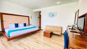 Een slaapkamer met een groot bed, een bank, een houten bureau en een televisie.