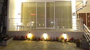 Een gebouw met twee verdiepingen, een balkon, grote ramen en buitenverlichting.