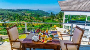Een eettafel met stoelen op een balkon met uitzicht op een mooi landschap.