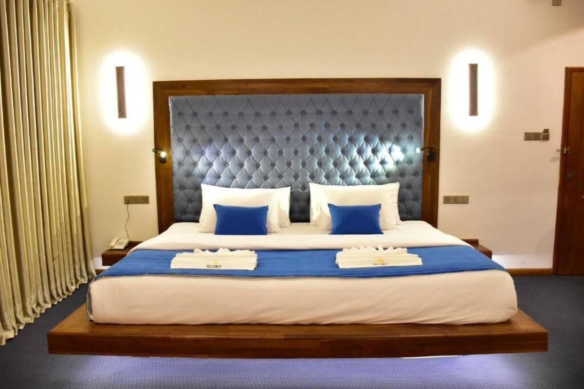 Una habitación de hotel con una cama grande, un cabecero de madera y dos mesitas de noche.