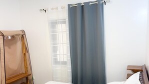 Ein ordentlich bezogenes Bett mit weißen Leinen, einem hölzernen Kopfstück und einer kleinen Holzregaleinheit mit einem Handtuch.