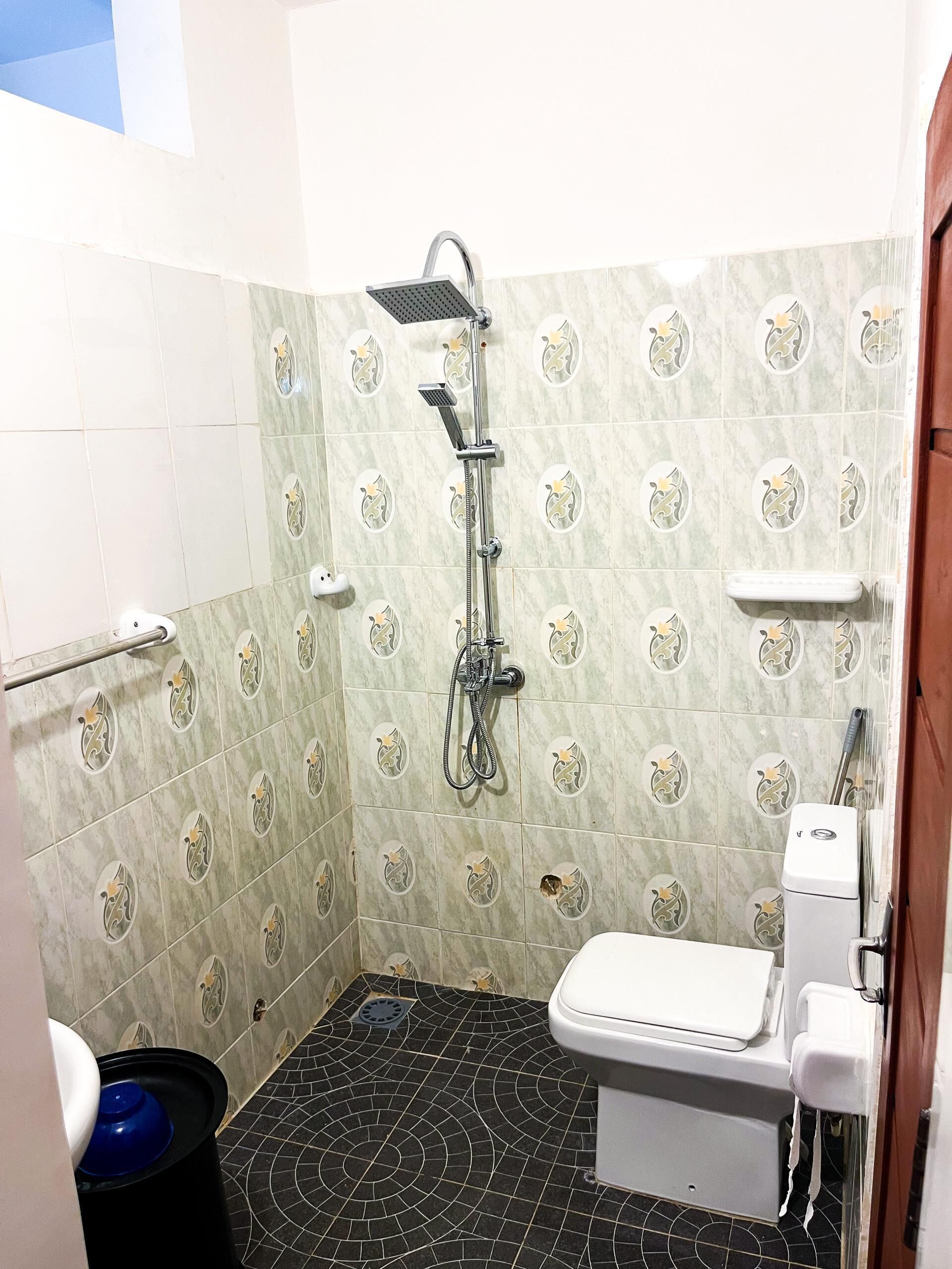 Un baño pequeño con ducha, inodoro y lavamanos.