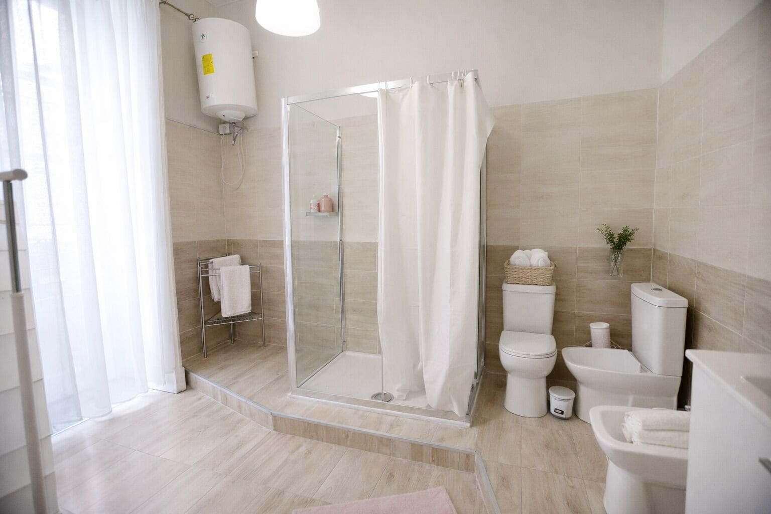 Un baño moderno con cabina de ducha de vidrio, inodoro, bidé y lavamanos.
