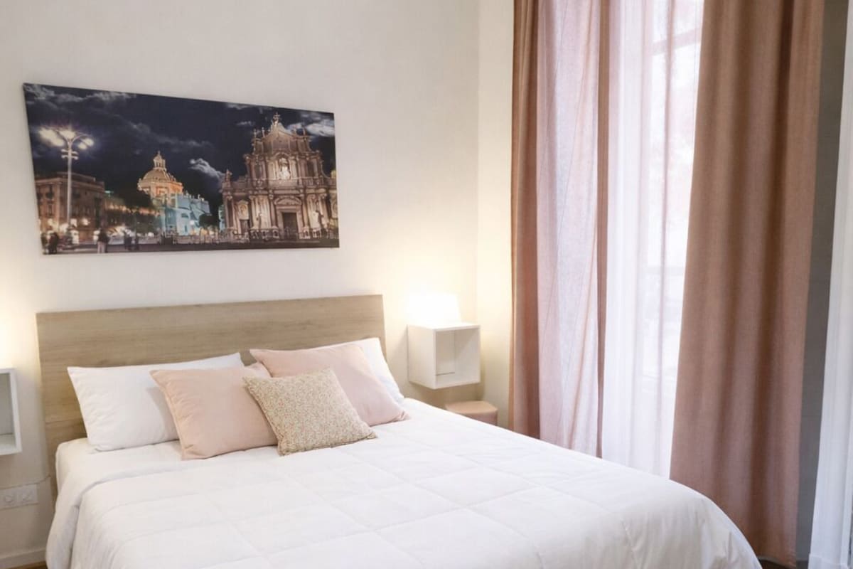 Una camera da letto con un grande letto, un affresco raffigurante il cielo notturno e una finestra con tende.