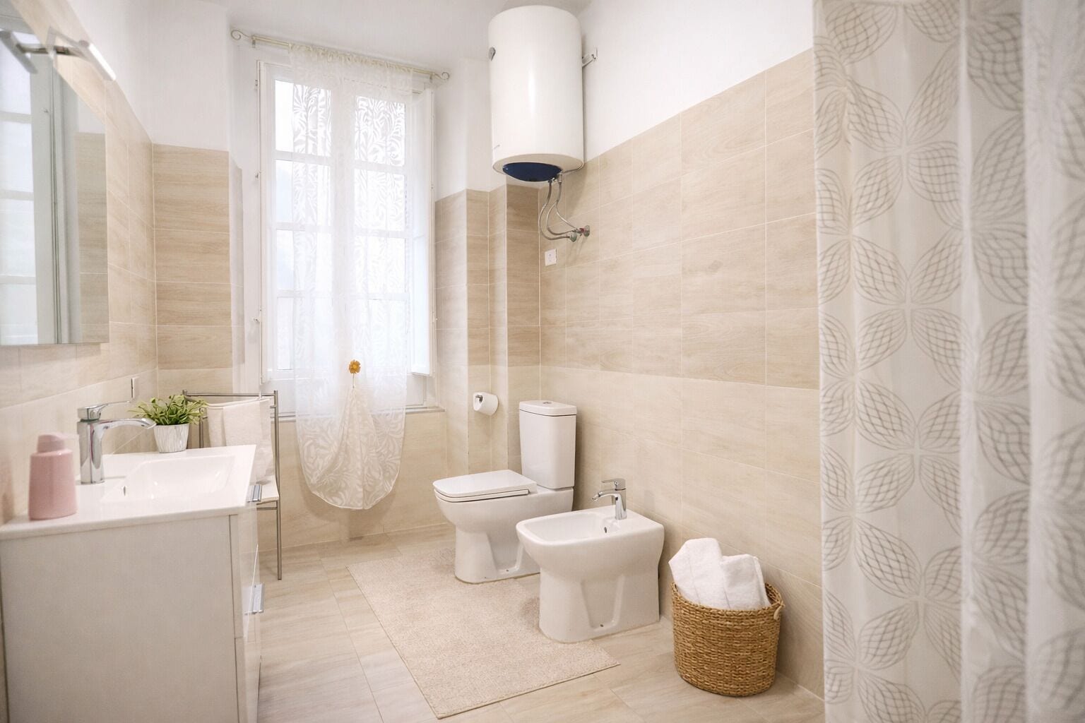 A bathroom with a toilet, bidet, sink, and a shower area.