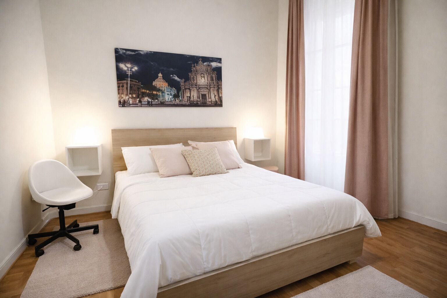 A hotel room with a large bed, bedside lamps, a chair, and a cityscape painting on the wall.