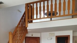 Una habitación con una escalera de madera, una mesa de comedor con sillas y una puerta.