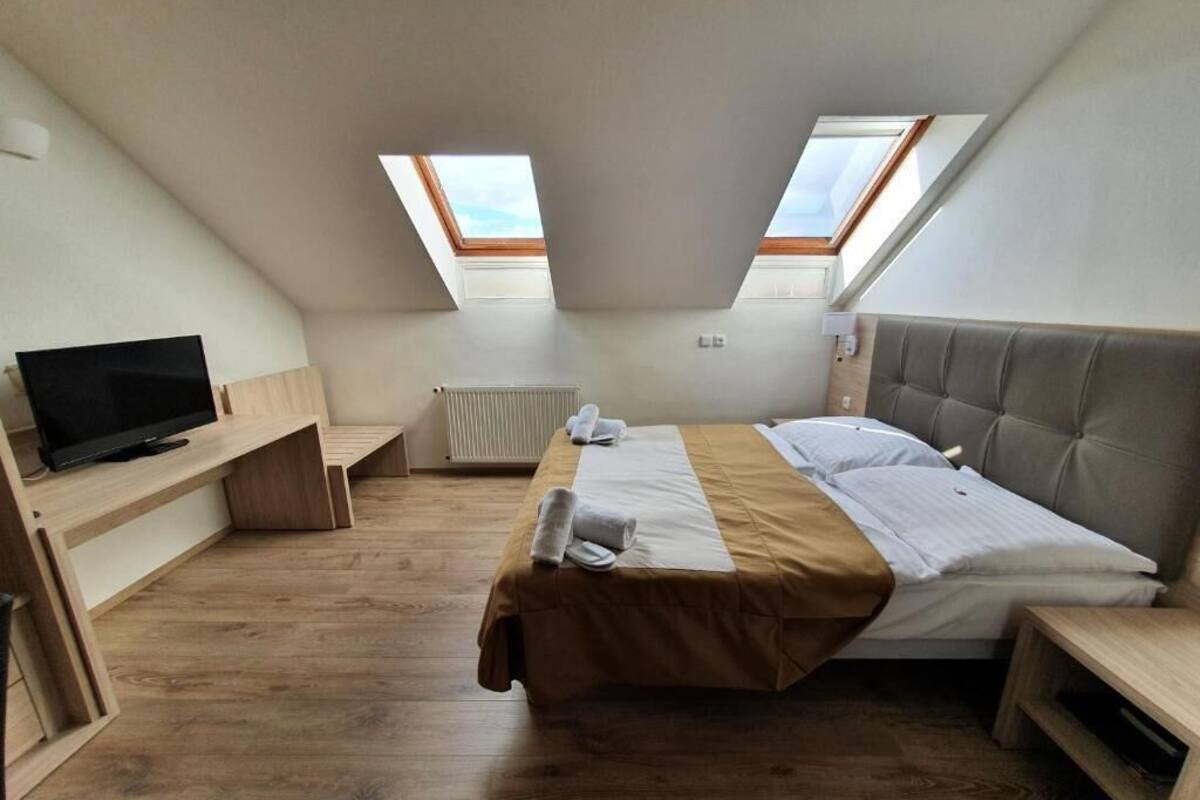 Una habitación con cama, televisión, escritorio y tragaluces.