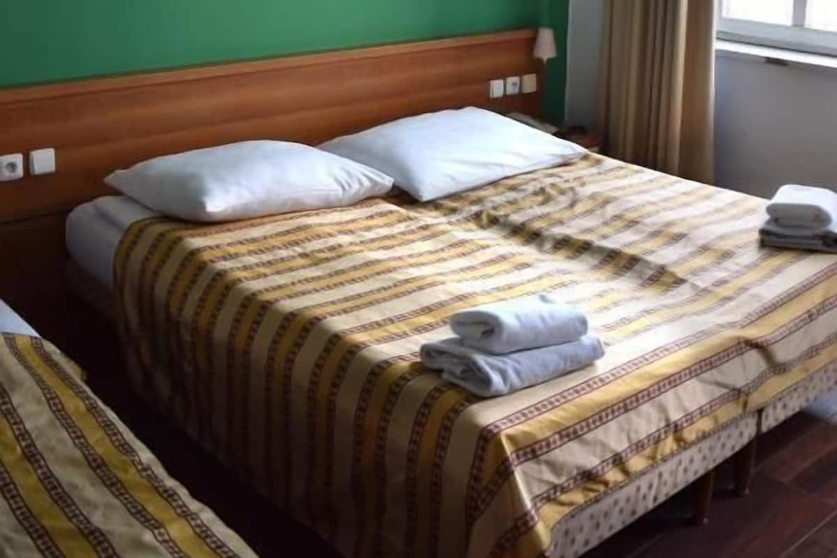 Habitación de hotel con dos camas, un cuadro en la pared y una ventana con cortinas.