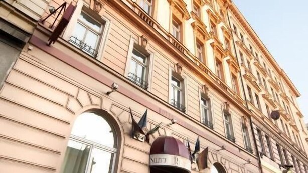 Un edificio de varios pisos con arquitectura clásica, que presenta ventanas en arco y una entrada central.
