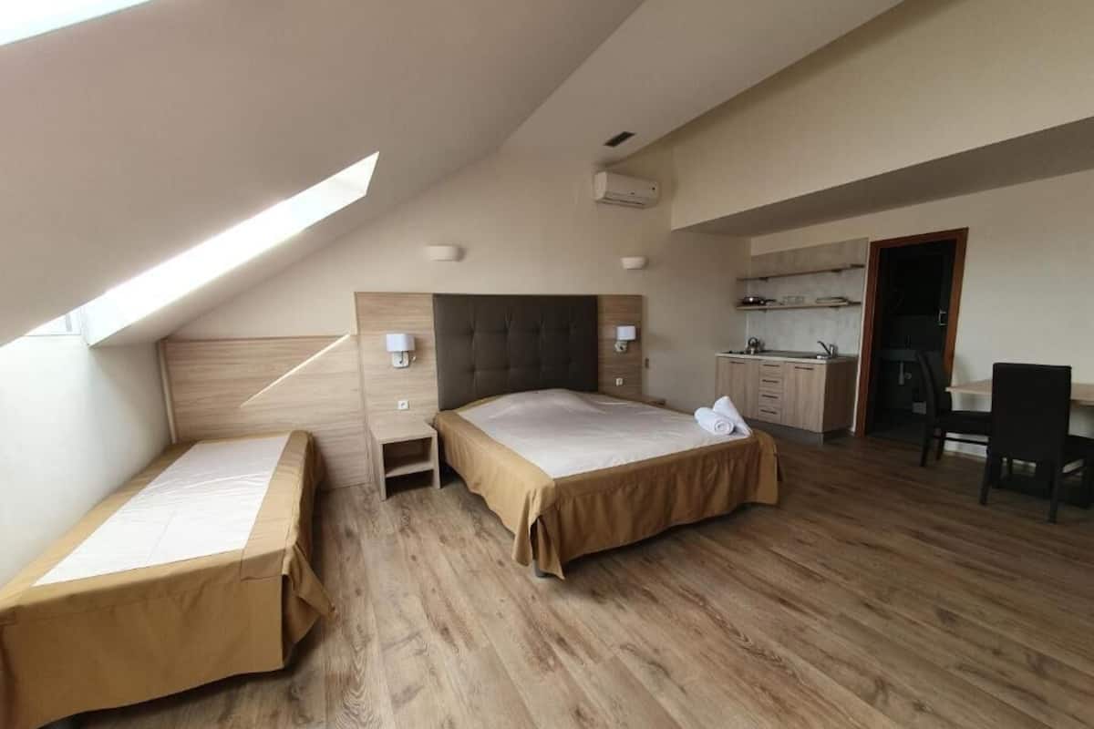 Un dormitorio con techo estilo loft, cama, escritorio y kitchenette.