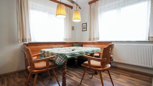 Een eetruimte met een houten tafel en stoelen, een bank en twee hanglampen.
