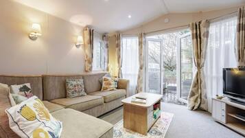 A living room with a sofa, a coffee table, a TV, and a sliding glass door leading to an outdoor area.