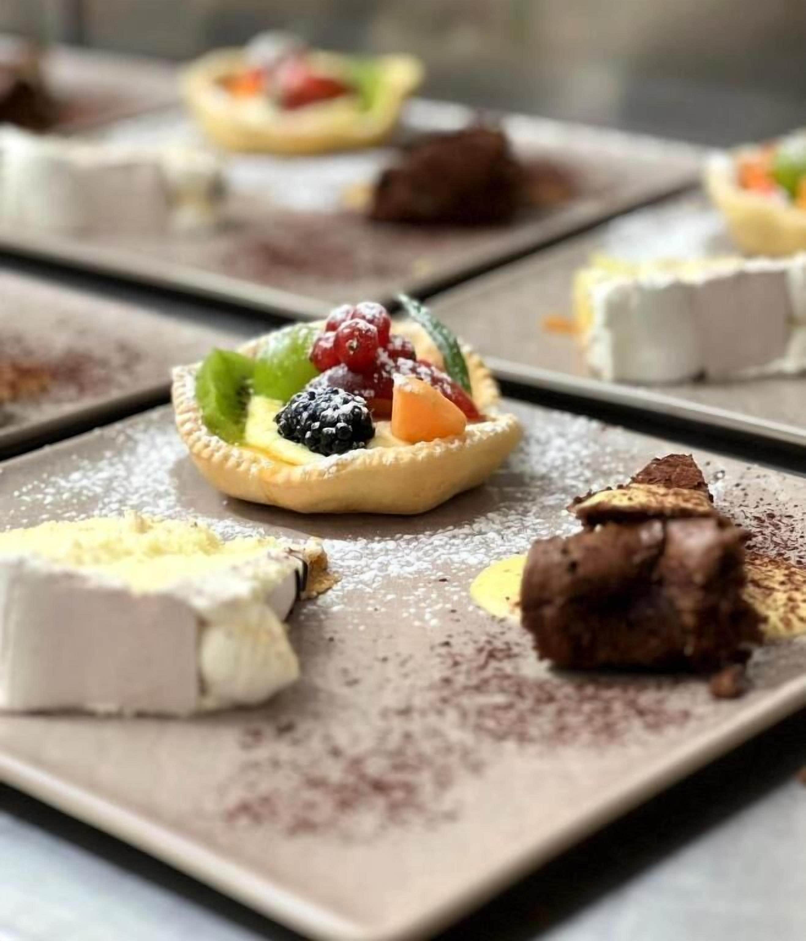 Een nagerechtenbord met een taart en diverse soorten fruit.