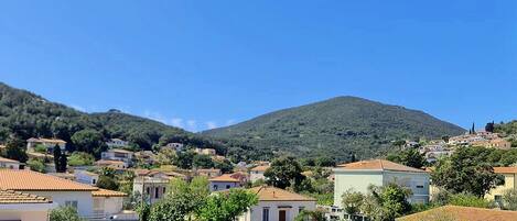 A residential area with houses, a hill in the background, and clear skies.