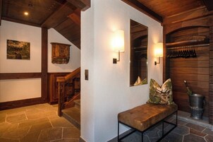 Una escalera de madera, un banco con cojines decorativos y apliques de pared.