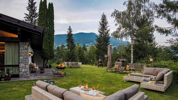 Eine Terrasse mit Gartenmöbeln, einer Steinmauer und Bergblick.