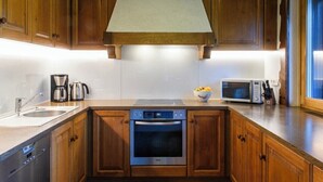 Eine Küche mit Holzschränken, einem Einbauofen, einer Mikrowelle und einer Kaffeemaschine.