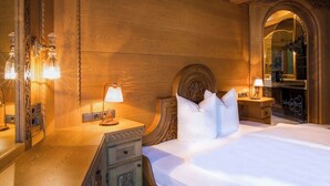 Ein Hotelzimmer mit einem großen Bett, Holzvertäfelung, einem Spiegel und einem Nachttisch mit Lampe.