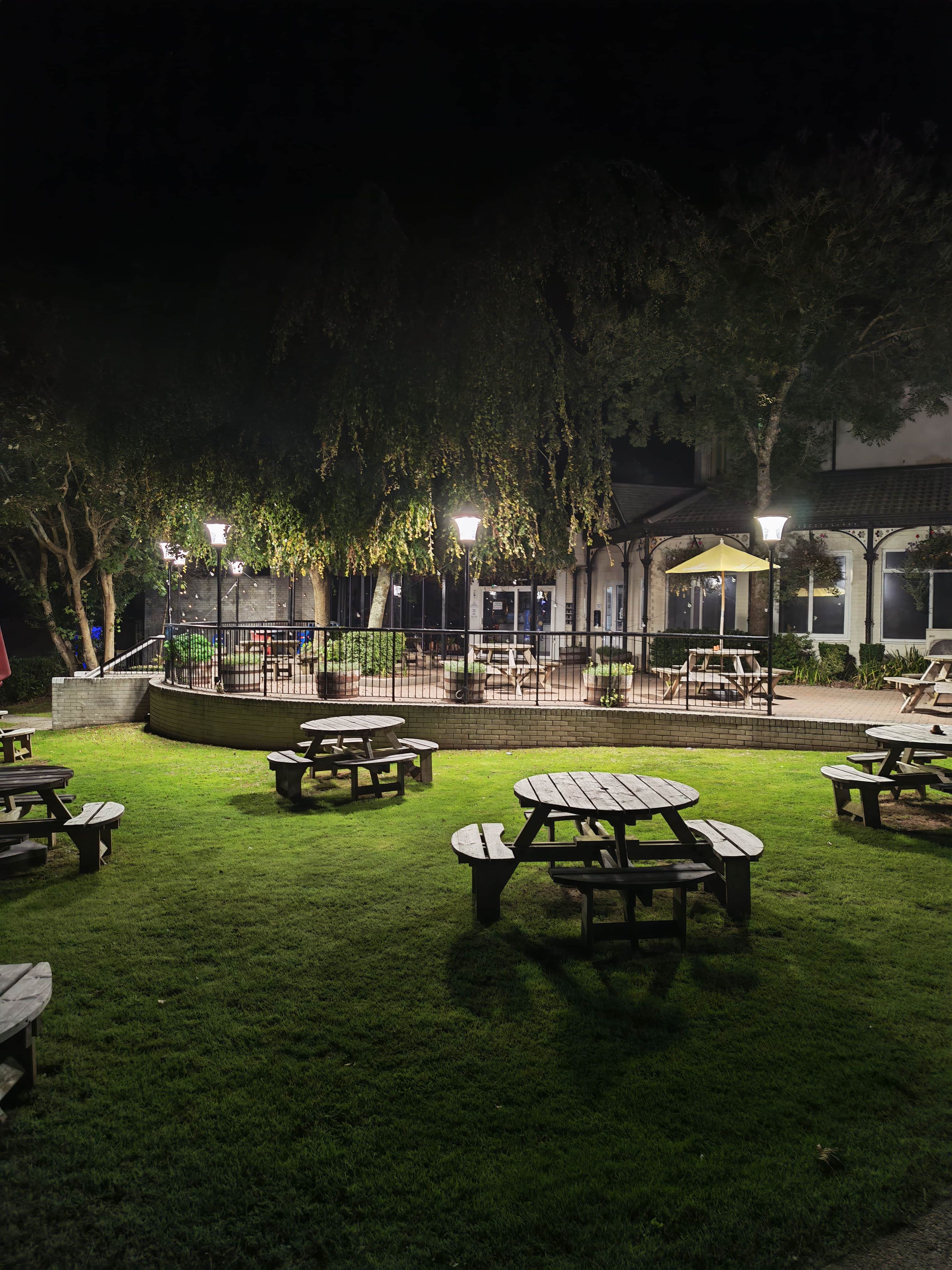 An outdoor patio area with picnic tables and a building in the background.