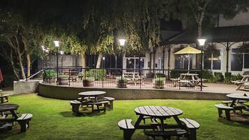 An outdoor patio area with picnic tables and a building in the background.