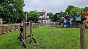 Un parque infantil con estructuras de madera para escalar y un tobogán.