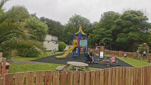Ein Spielplatz mit Rutsche, Schaukeln und einer Kletterkonstruktion.