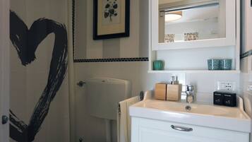 Ein Badezimmer mit Toilette, Waschbecken, Waschtisch und einer Wanddekoration in Herzform.