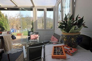 A sunlit room with a bed, a potted plant, and a window overlooking a parking area. - Lùlù Guest House  (Dernice)