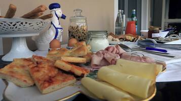 Ein Esstisch mit verschiedenen Speisen, darunter Brot, Käse, Eier und eine dekorative Keramikfigur.
