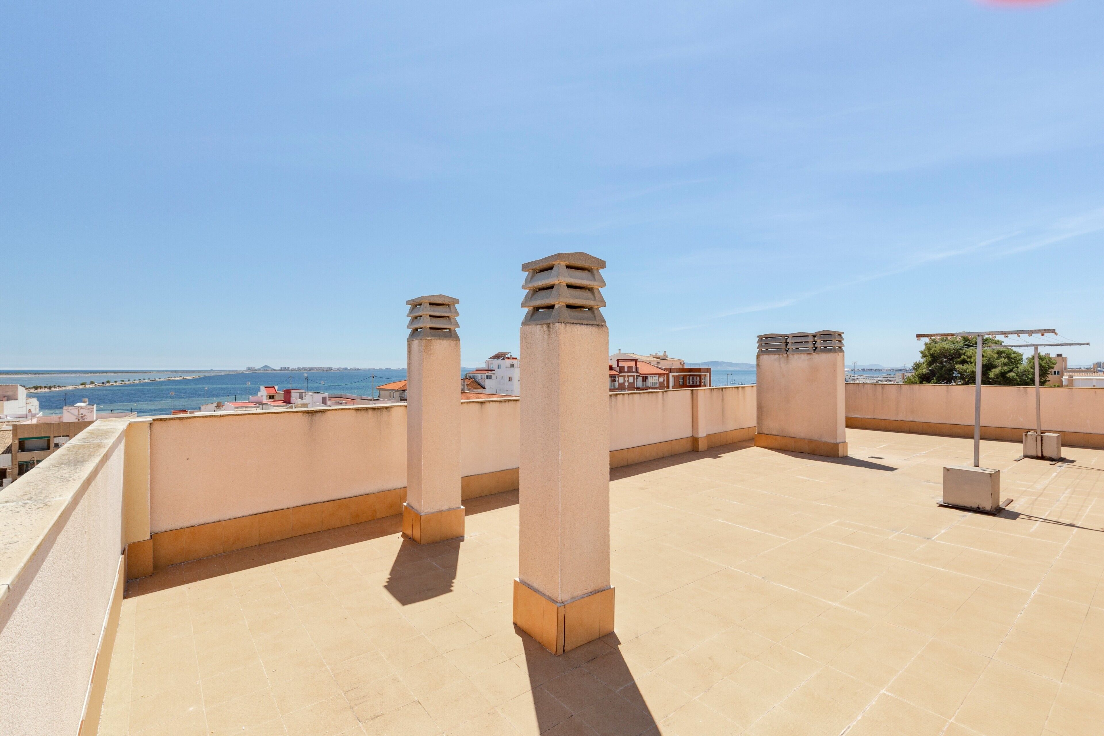 Terraza en la azotea con vistas despejadas al mar y edificios a lo lejos.