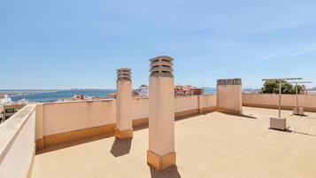 Terraza en la azotea con vistas despejadas al mar y edificios a lo lejos.