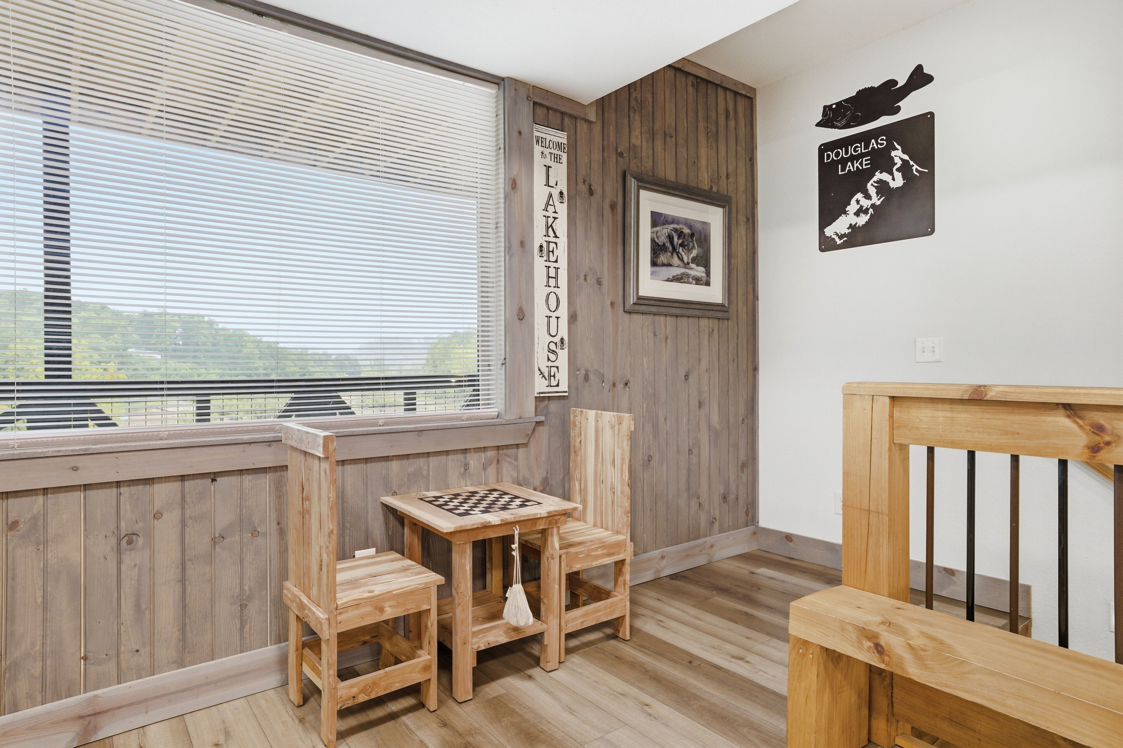A room with a wooden bench, a chess table, and a view of the outdoors.