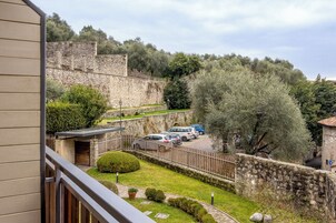 Un patio con paredes de piedra, coches estacionados y vistas de un edificio histórico de piedra.