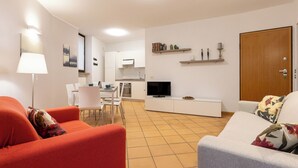 A modern living room with a dining area, a TV, and a kitchen in the background. - Lemon House 3 by Wonderful Italy (Gardone Riviera)