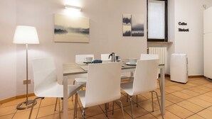 A dining area with a table, chairs, a lamp, and a refrigerator. - Lemon House 3 by Wonderful Italy (Gardone Riviera)