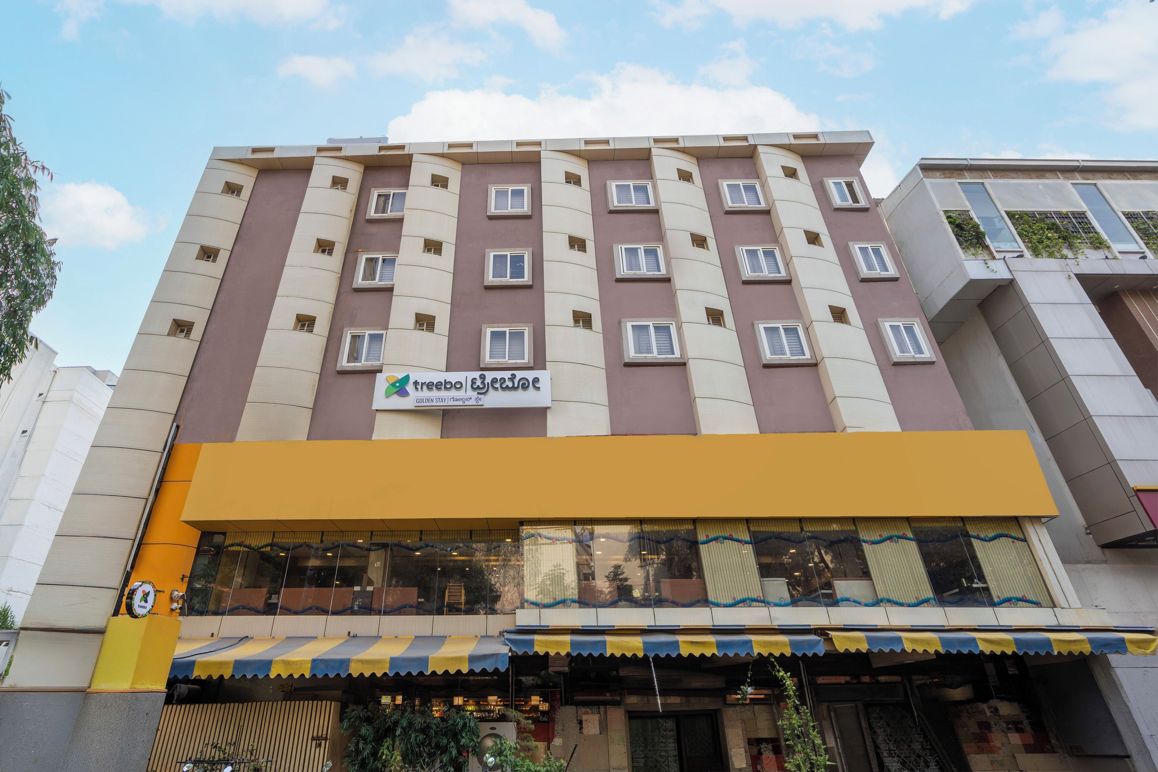 A multi-story hotel with a prominent sign, a yellow awning, and a visible storefront.
