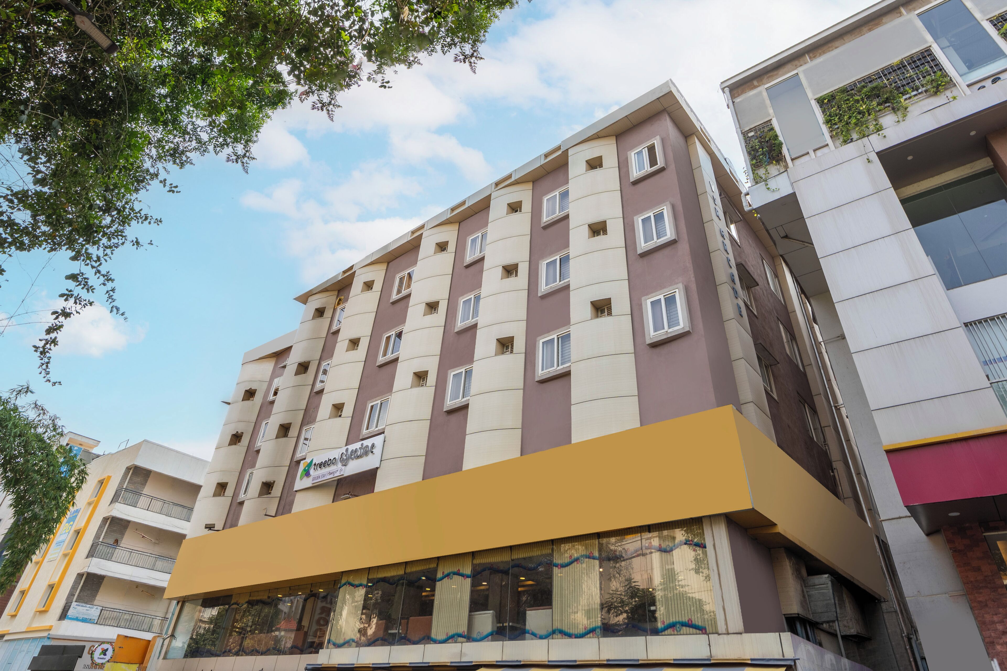 A multi-story hotel with a yellow facade, multiple balconies, and a sign indicating it is a hotel.