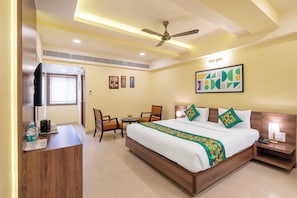 A hotel room with a bed, a desk, a chair, a television, and a ceiling fan.