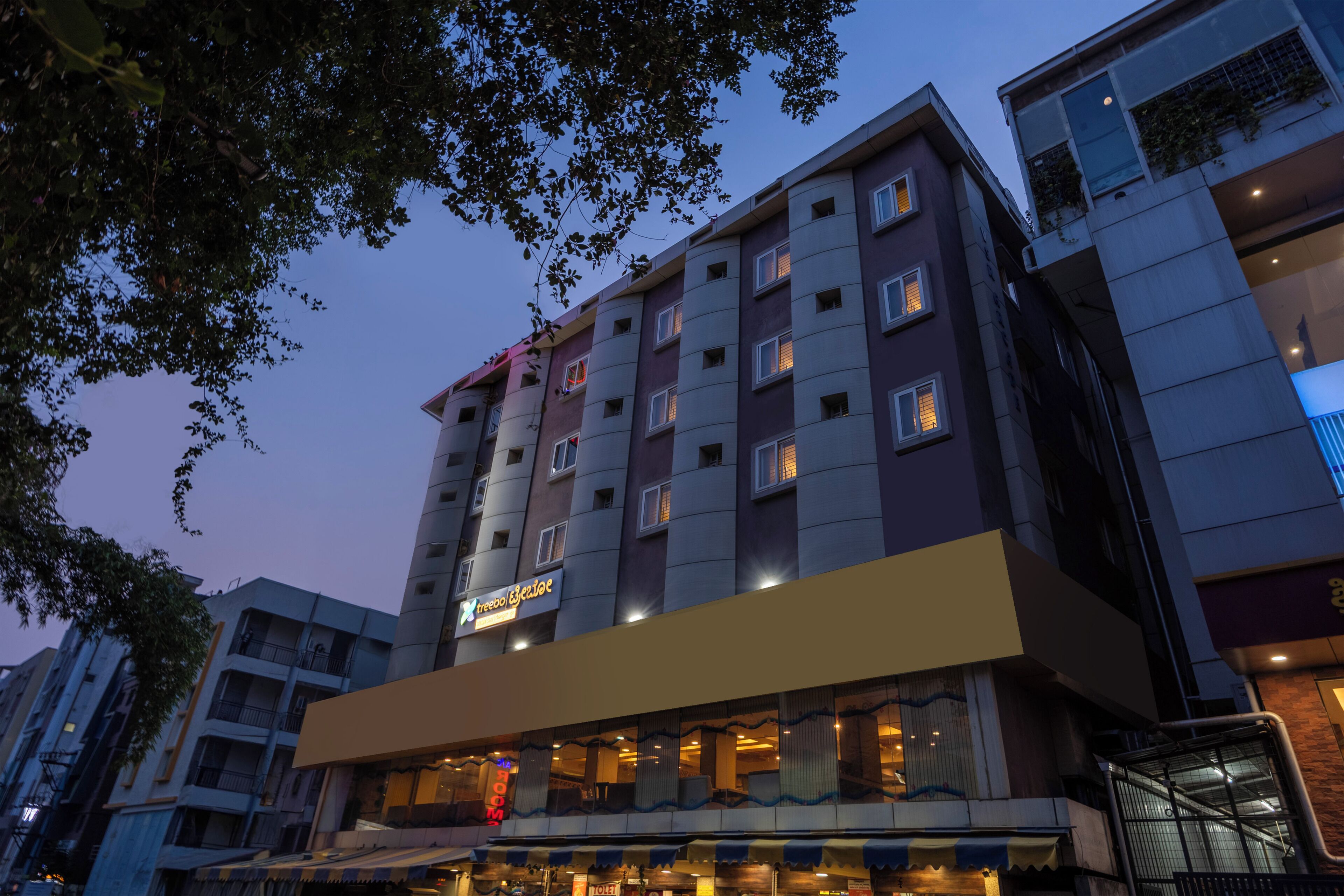 A multi-story hotel with a prominent 'X' logo, balconies, and a ground-level restaurant.