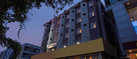 A multi-story hotel with a prominent 'X' logo, balconies, and a ground-level restaurant.