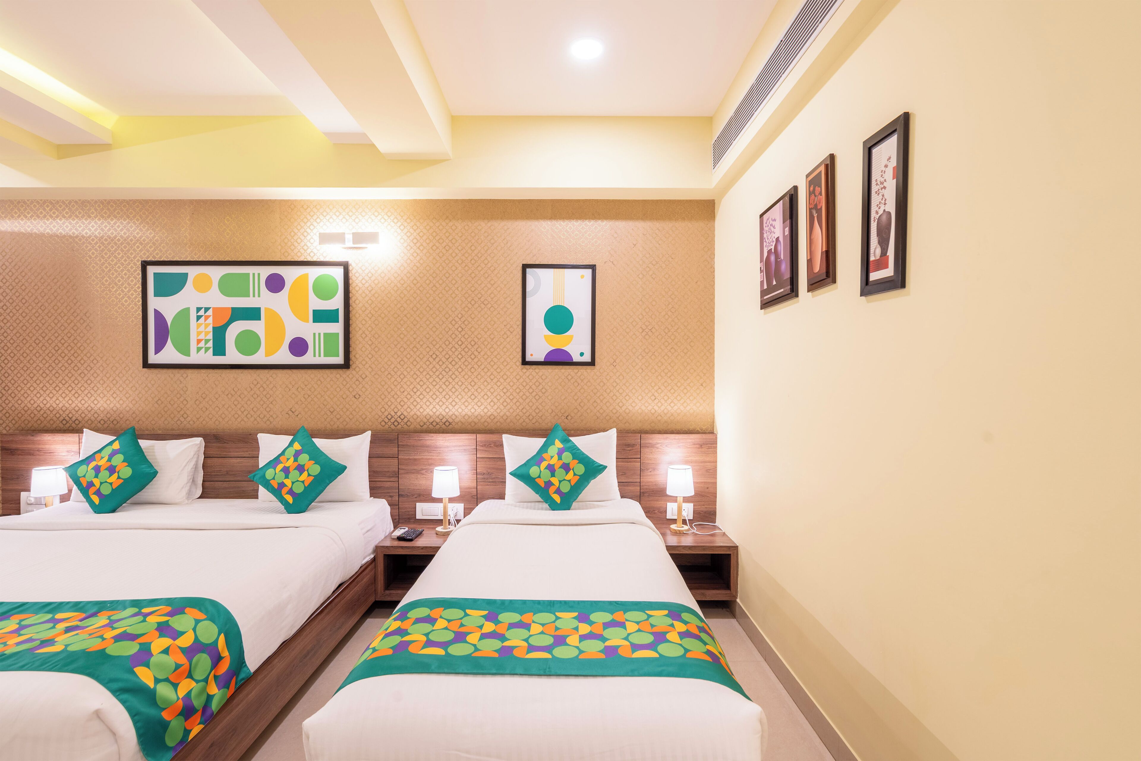A hotel room with two beds, nightstands, wall art, and a patterned carpet.