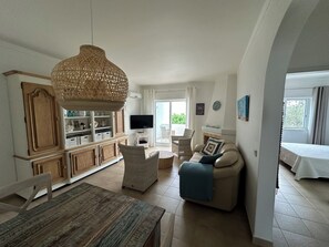 Ein geräumiger Wohnbereich mit Esstisch, Sofa und Fernseher.