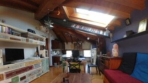 A cozy living room with a wooden coffee table, a red sofa, and a television. - B&B Mirò (Pieve di Soligo)